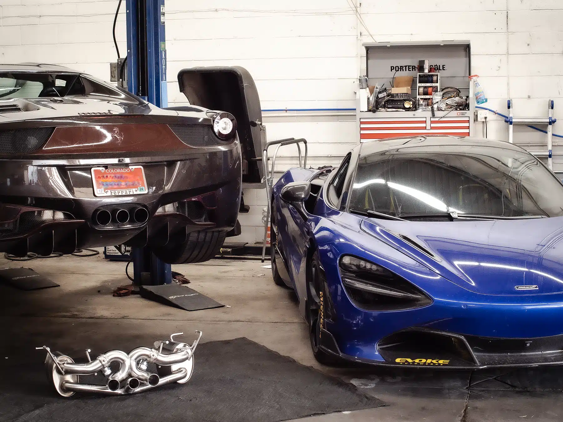 Blue McLaren being serviced alongside another supercar in a workshop at Evoke Autowerks in Englewood, CO.