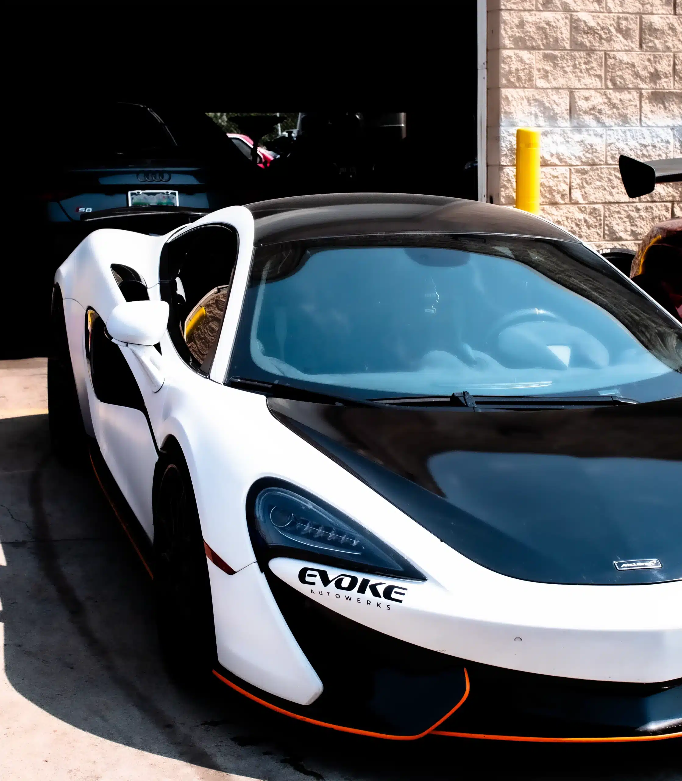 White McLaren supercar with black accents and "Evoke" branding, highlighting custom performance enhancements.