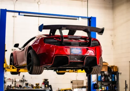 Red McLaren on lifts in shop in Englewood, CO.